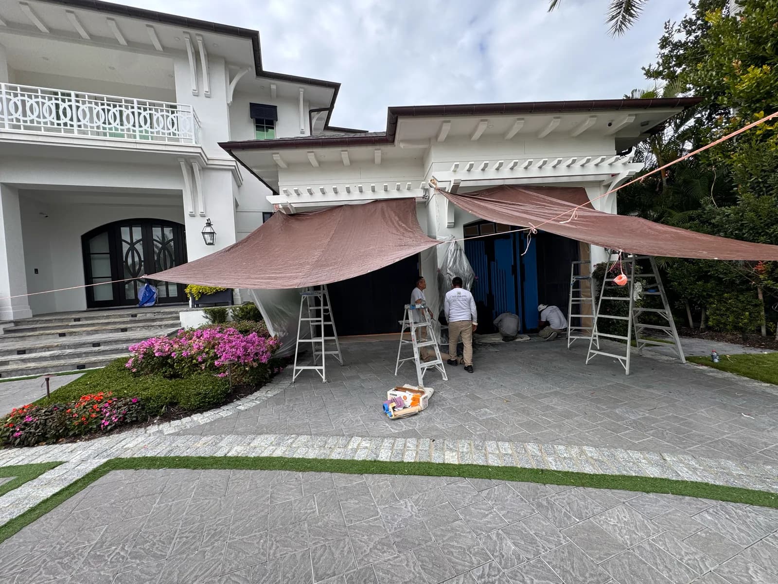 Crew set up under shade canopies on a driveway at the start of a job