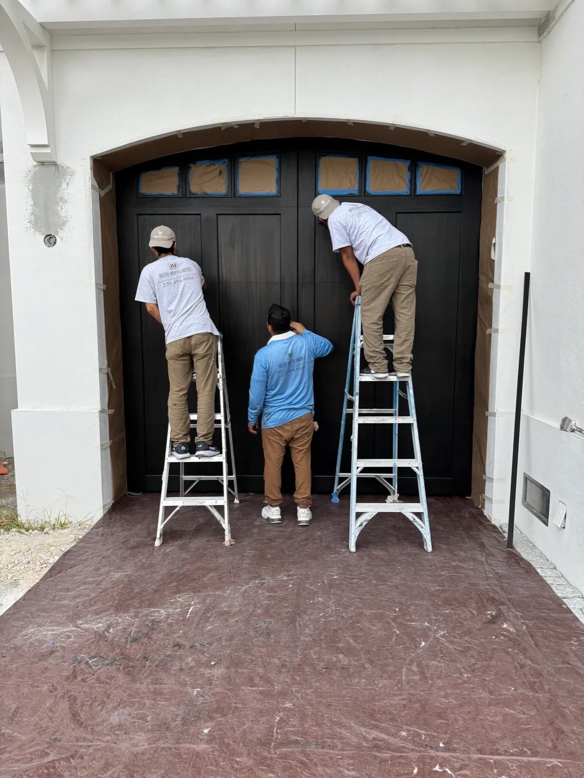 Crew working a pair of garage doors from step ladders