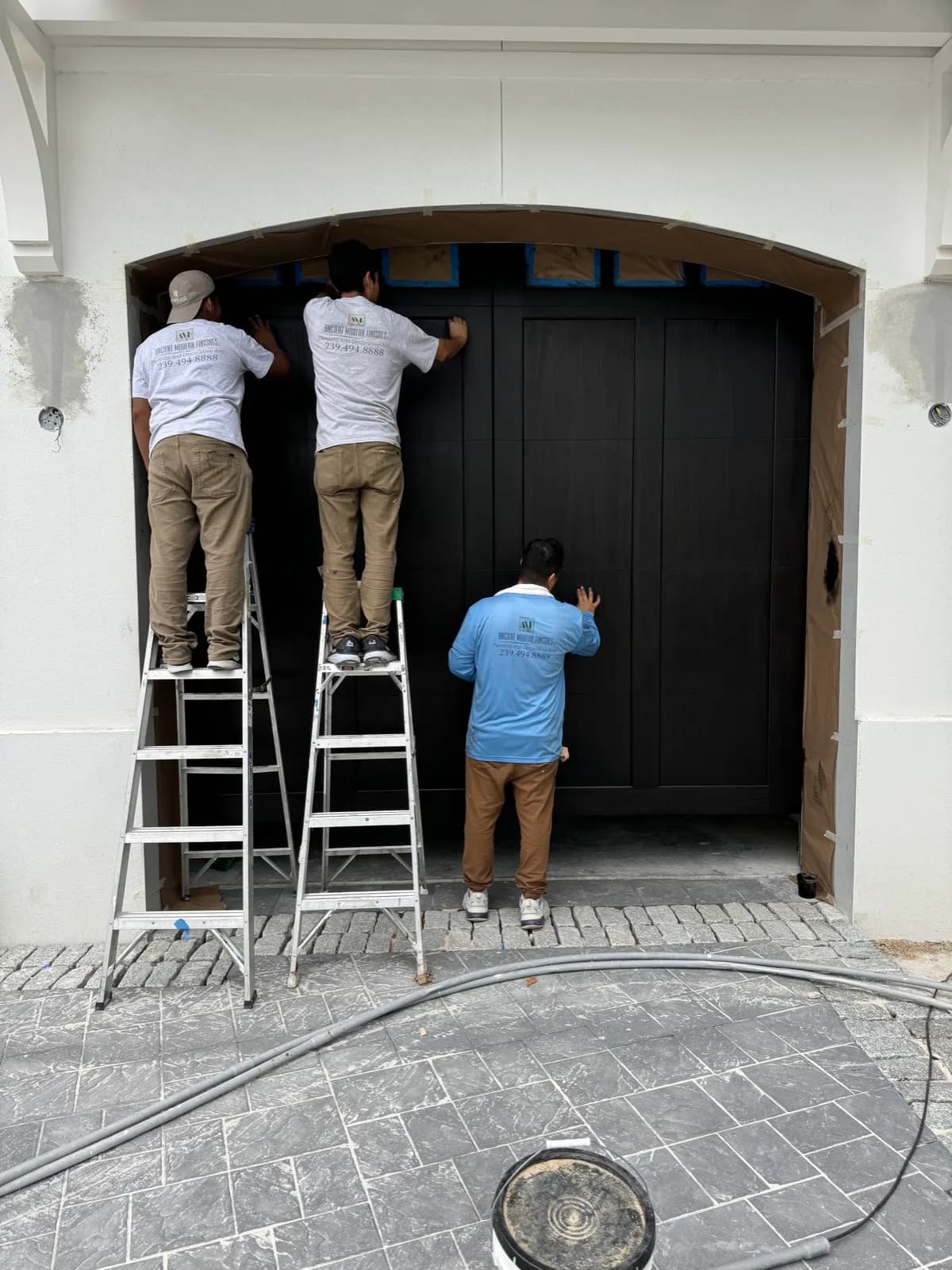 Crew finishing a garage door under full masking