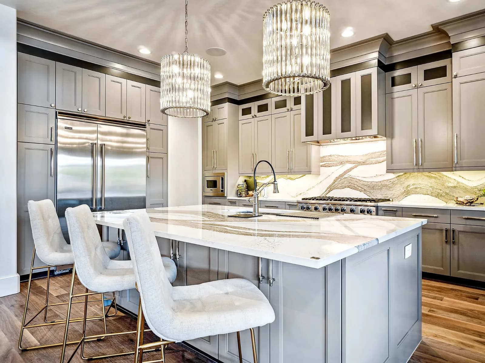 Kitchen with refinished cabinetry, a marble island and glass pendants
